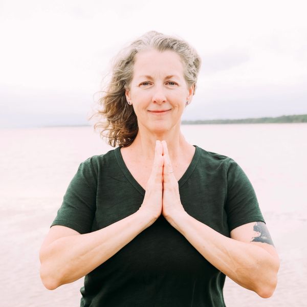 Woman practicing meditation outdoors by the water.