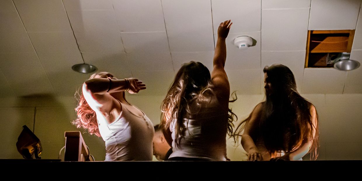 Three women enjoying a lively moment under warm lighting indoors.