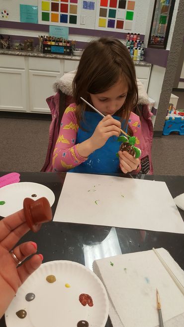 Girl painting a small craft project indoors.