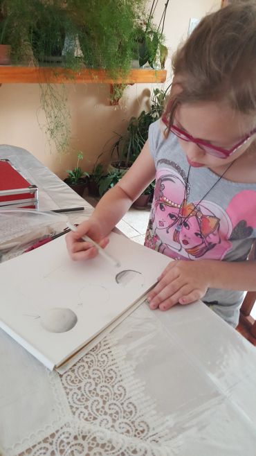 Child with glasses drawing on paper.