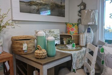 Cozy rustic corner with wicker baskets, ceramic vases, and a floral pillow on a wooden table.