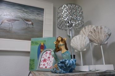Mermaid figurine on a wooden table with coastal-themed decor.