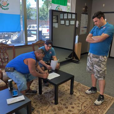 Signing a contract Mikelly seated with customer, Hami standing up watching closely.