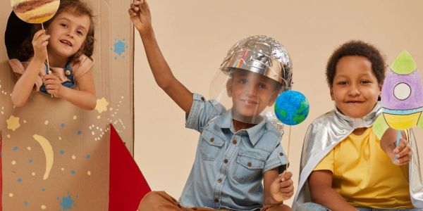 Children playing space explorers with planets and rockets.