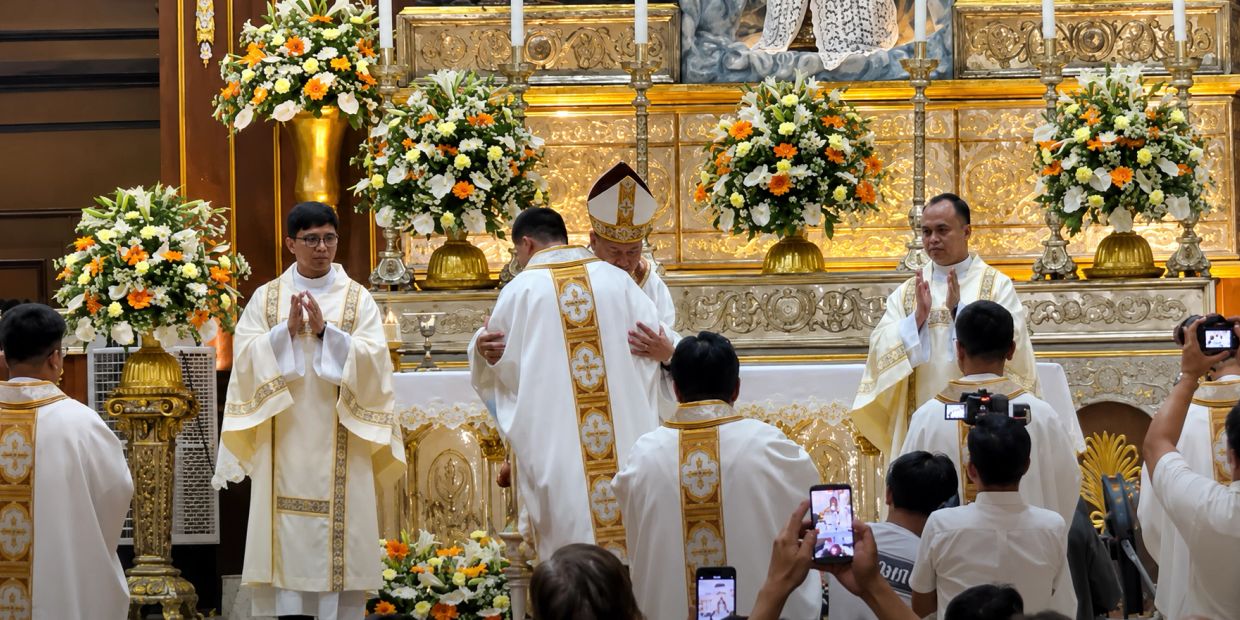 Clergy members in white and gold vestments during a religious ceremony in a beautifully decorated church.