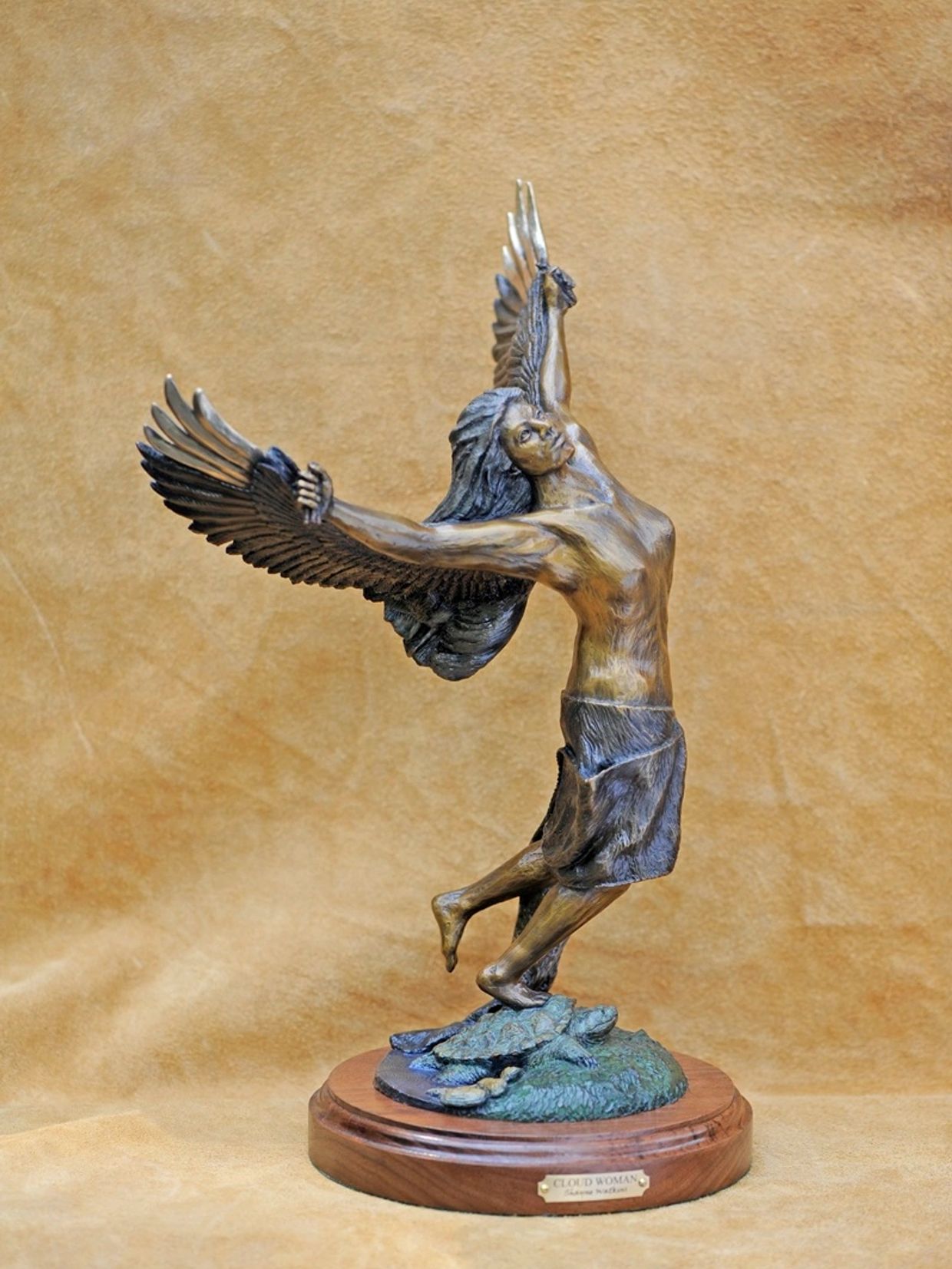 Bronze statue of a winged woman on a wooden base.