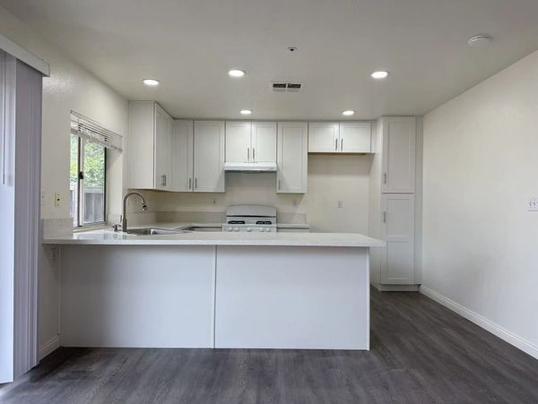 Modern white kitchen with island and gray flooring.