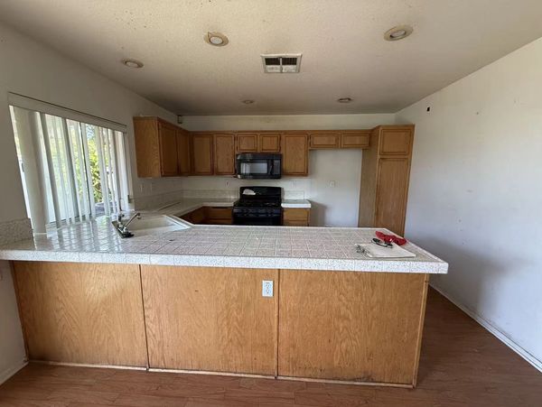 Empty kitchen with wooden cabinets and tile countertops.