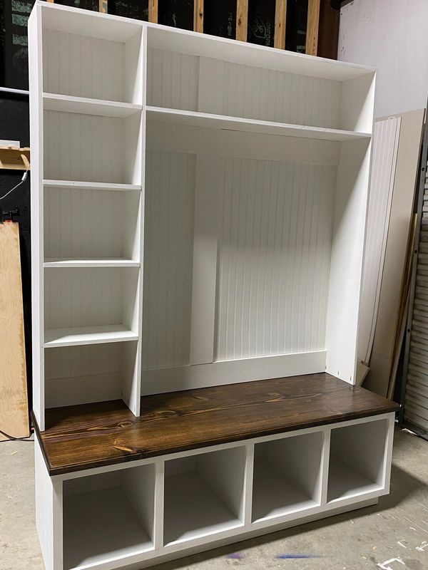 White and wood entryway storage bench with cubbies and shelves.