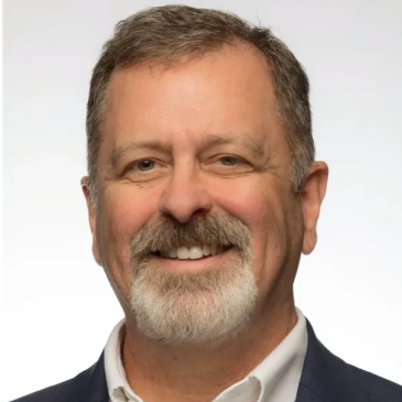 Smiling middle-aged man with a beard and suit.