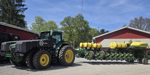 Large green tractor with agricultural machinery attached.