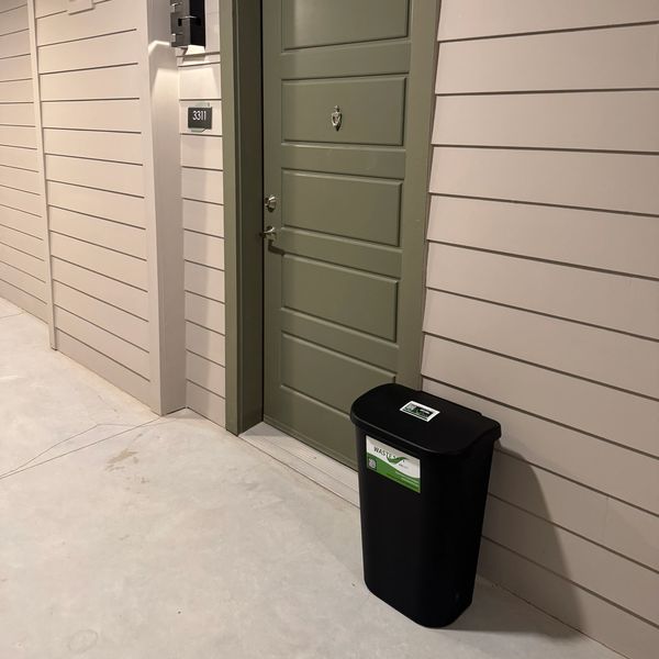 A standard Waste Wave Valet bin placed outside a resident’s door for scheduled pickup.