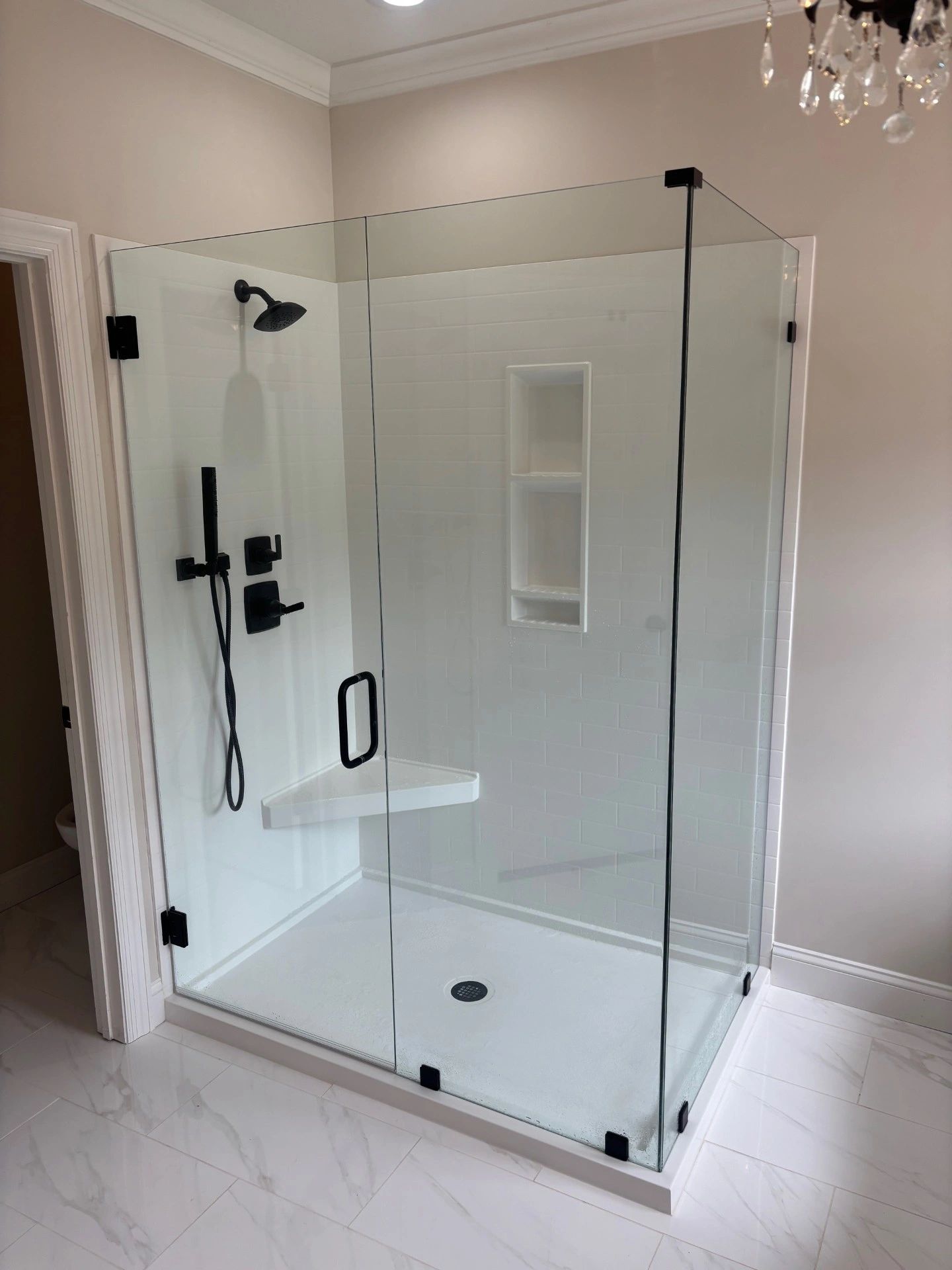 Modern glass shower enclosure with black fixtures.