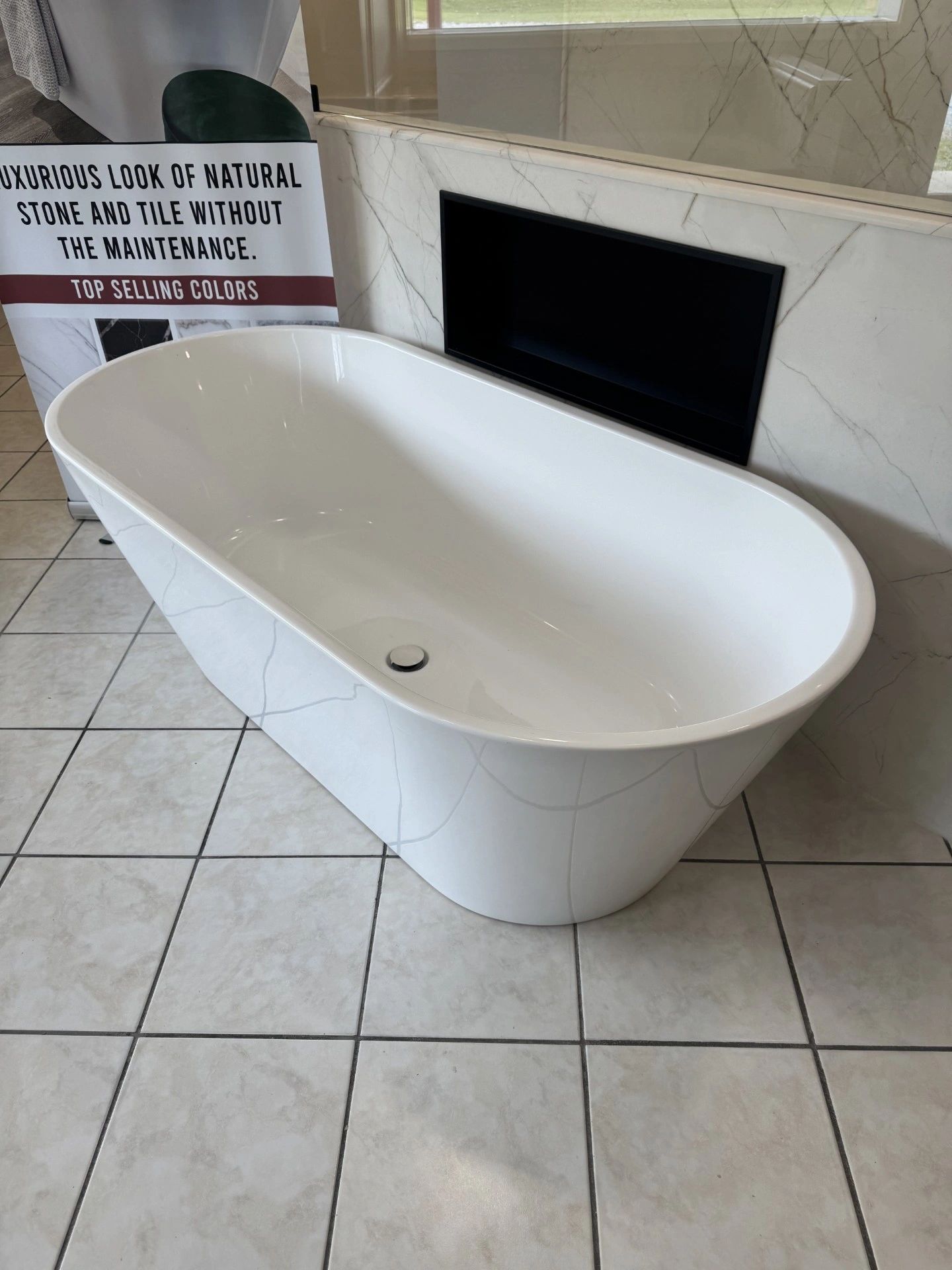 Modern white bathtub with marble-patterned tile.