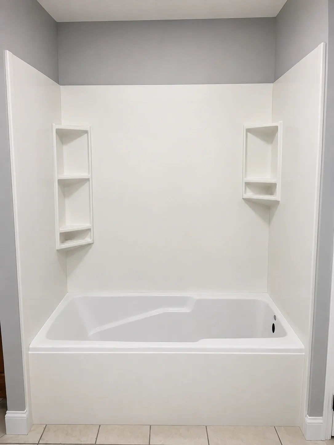 Empty white bathtub with shelving in a minimalist bathroom.