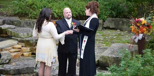 Couple getting married outdoors with an officiant.