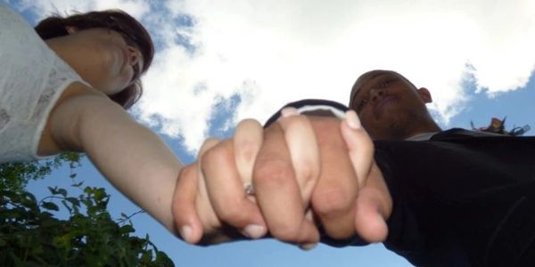 Couple holding hands against the sky.