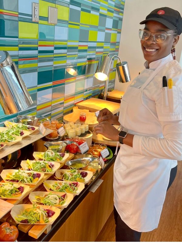 Chef preparing salad dishes at a buffet.