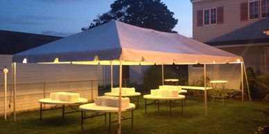 White tent with round tables and lighting for outdoor event