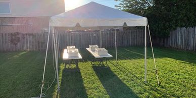 White tent with banquet tables for outdoor event