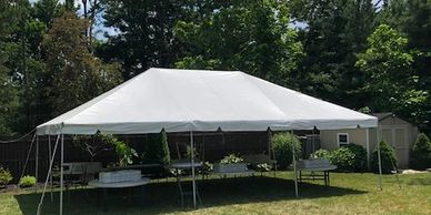 Large white tent with round tables set up for a backyard party