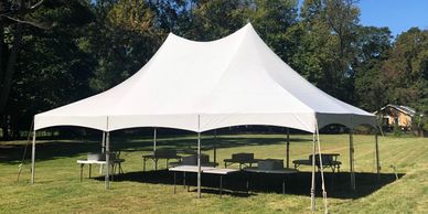 High-peak white tent with round and banquet tables set up for an outdoor event