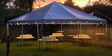 White tent with folding tables and lighting for outdoor event
