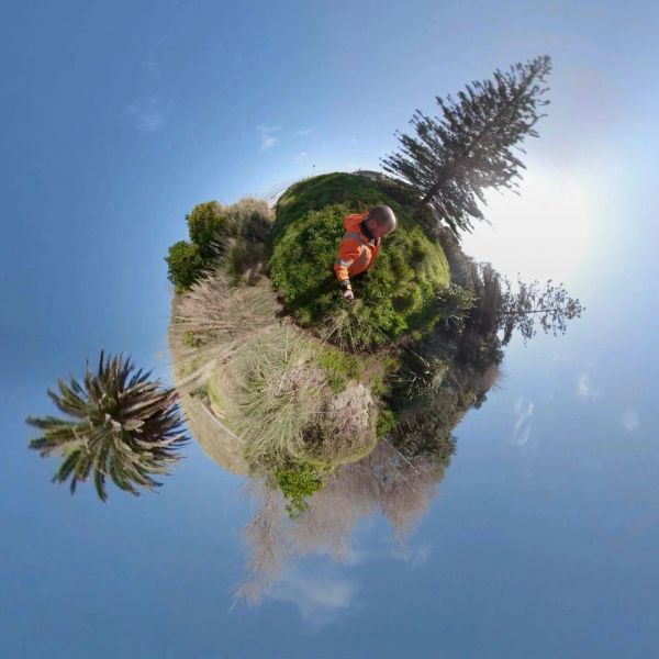360-degree tiny planet view with a child in an orange jacket surrounded by nature.