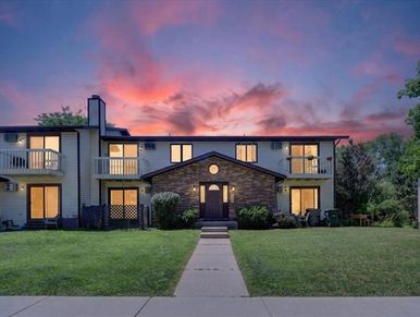 Two-story house at sunset with glowing windows.