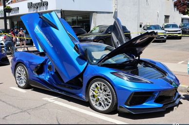 Blue sports car with doors and hood open.