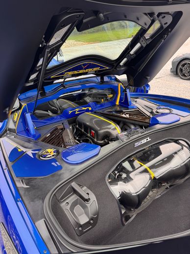 Open rear of blue sports car showcasing engine and storage.