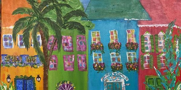 Colorful painted houses with flower pots and a palm tree.