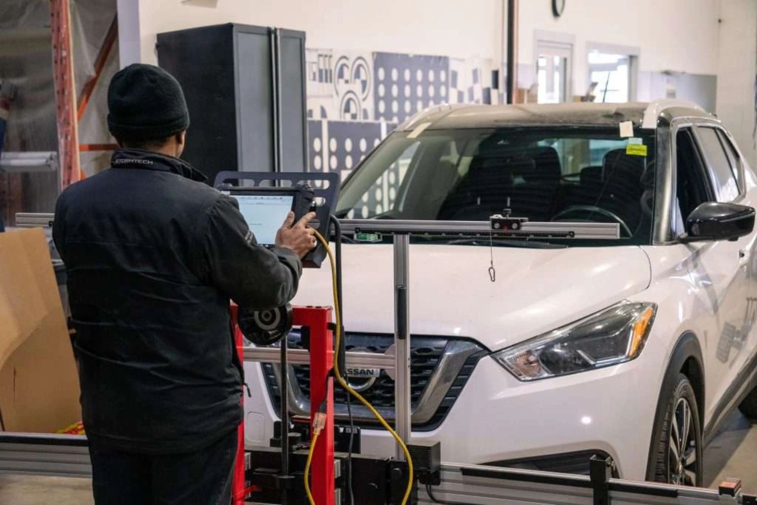  technician performing an ADAS camera calibration on a SUV using computerized calibration equipment.