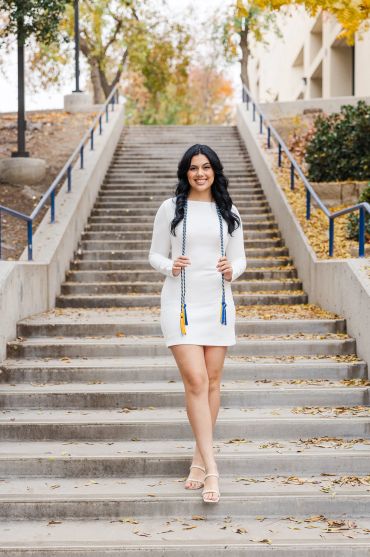Young woman standing on outdoor stairs in a white dress.