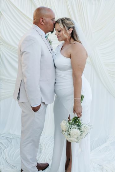 Groom kisses bride's forehead during wedding.