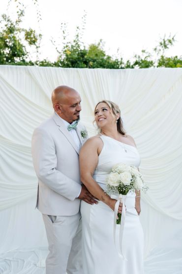 Newlywed couple smiling during outdoor wedding ceremony.