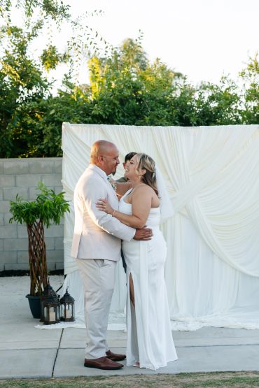 Bride and groom embracing at outdoor wedding.