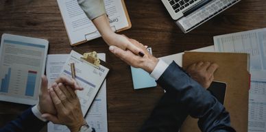 Three coworkers: two shaking hands and one clapping.