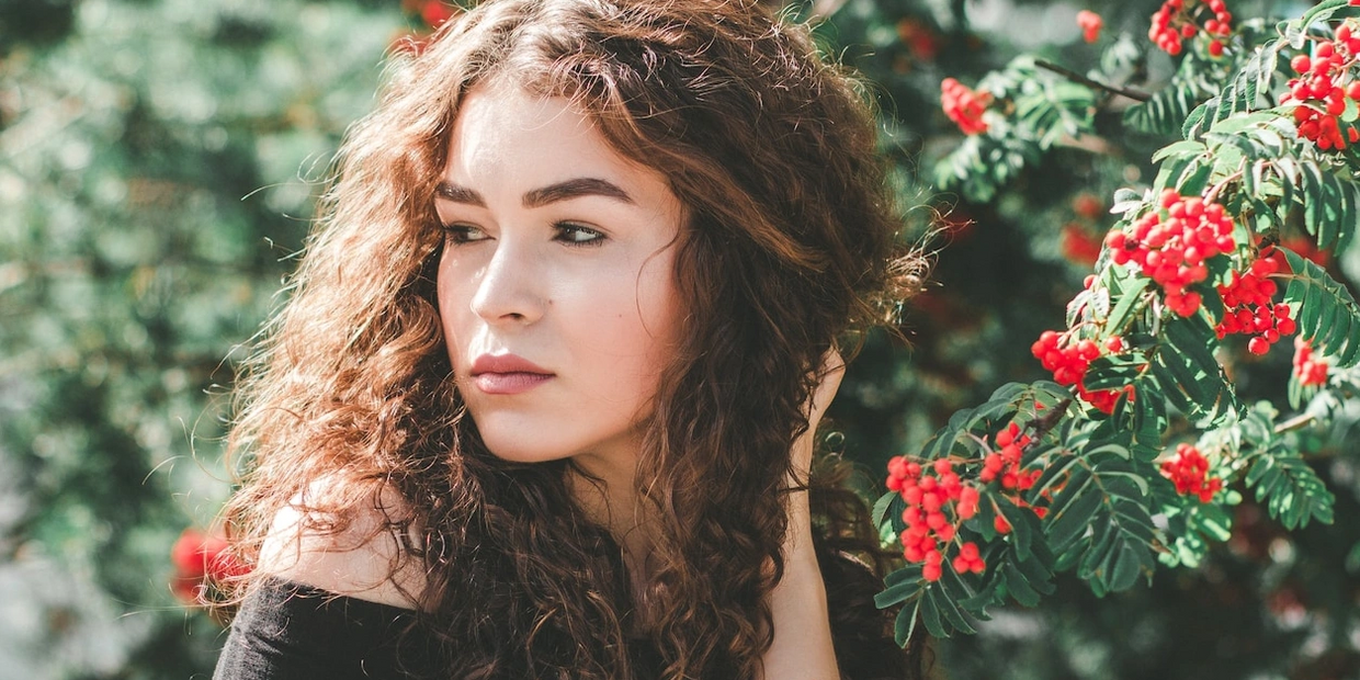 young girl standing by flower bush in the sun