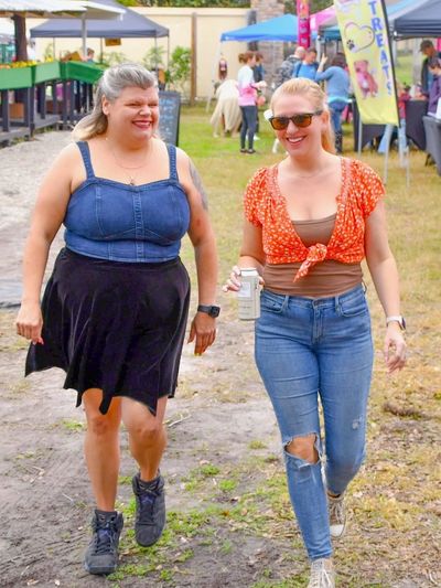 Two women smiling and walking outdoors at a casual event.