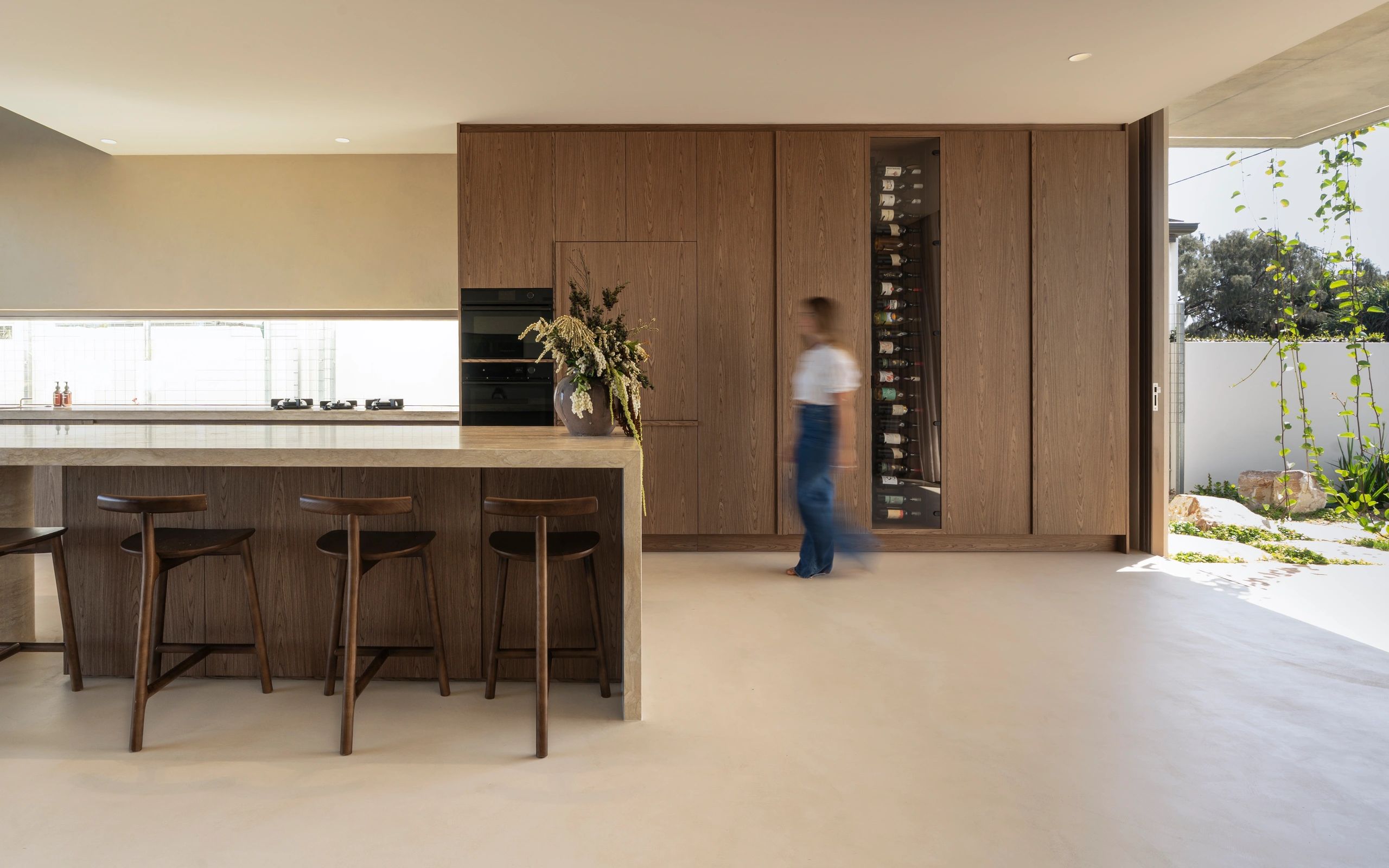 Modern kitchen with wood cabinetry and a blurred person walking.