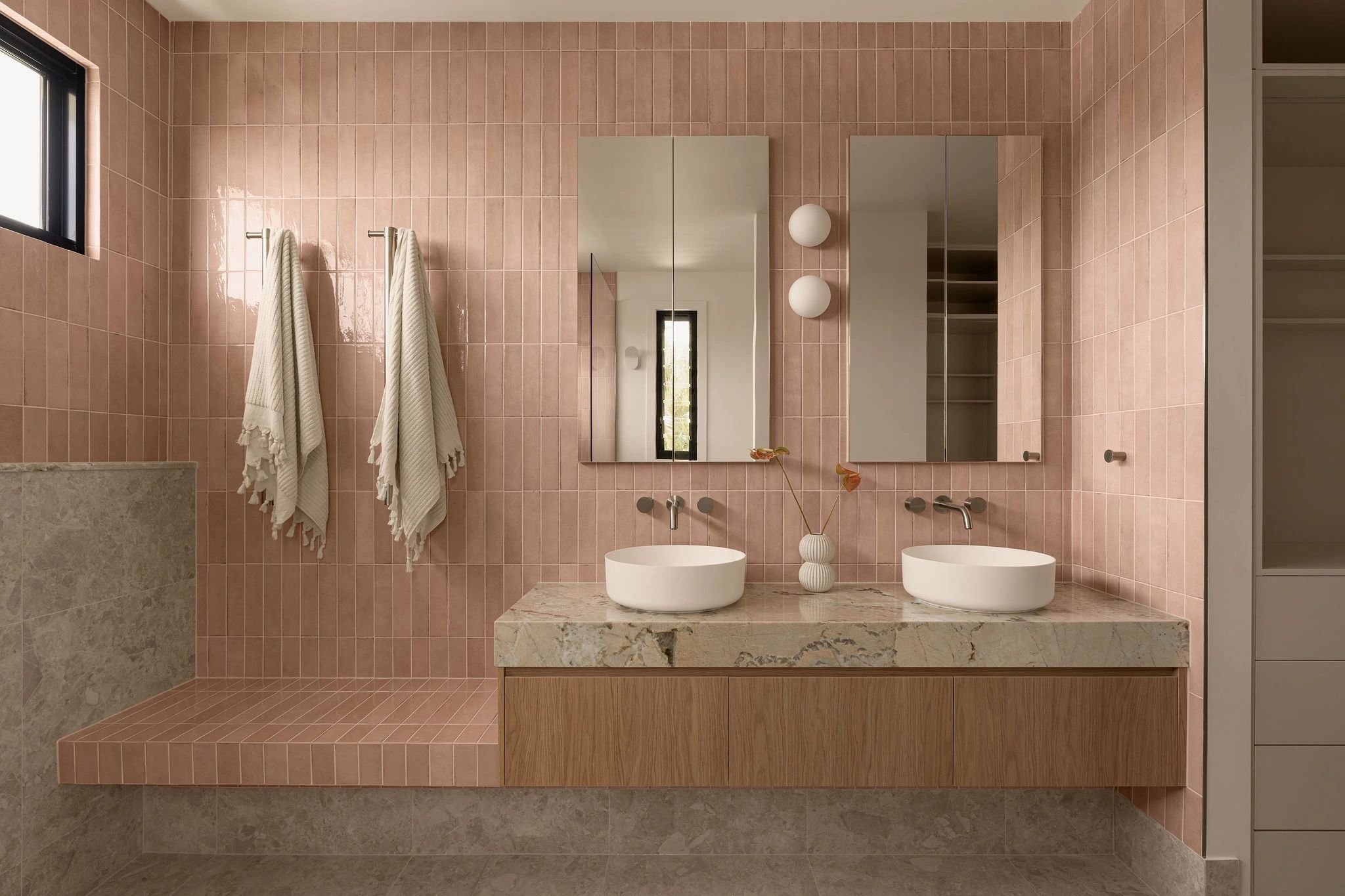 Modern bathroom with pink tiles and dual mirrors.