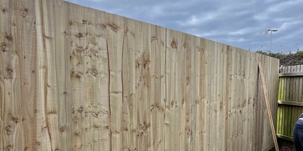 Newly installed wooden fence under a cloudy sky.