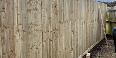 Newly installed wooden fence under a cloudy sky.