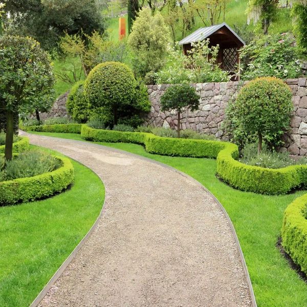 Curved garden path lined with neatly trimmed hedges and topiary trees.