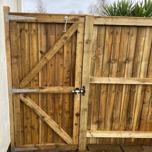 Wooden garden gate and fence with metal hinges and a padlock.