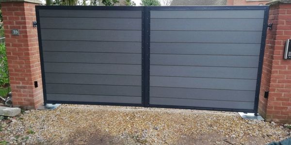 Modern gray double driveway gate between brick pillars.