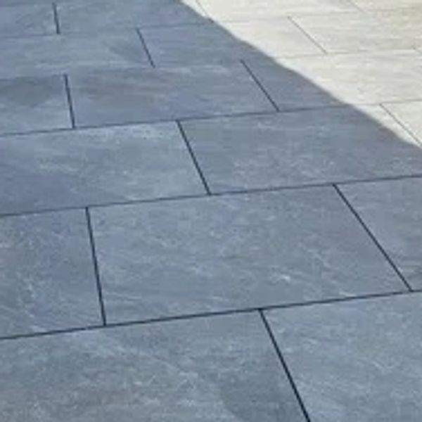 Newly paved patio with gray stone tiles and wooden fencing.