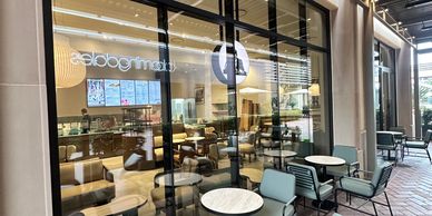 Modern outdoor seating area with green cushioned chairs and small round tables.