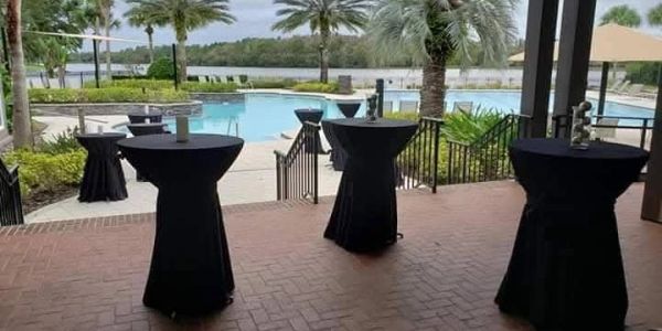 Poolside area with tall tables covered in black cloth.